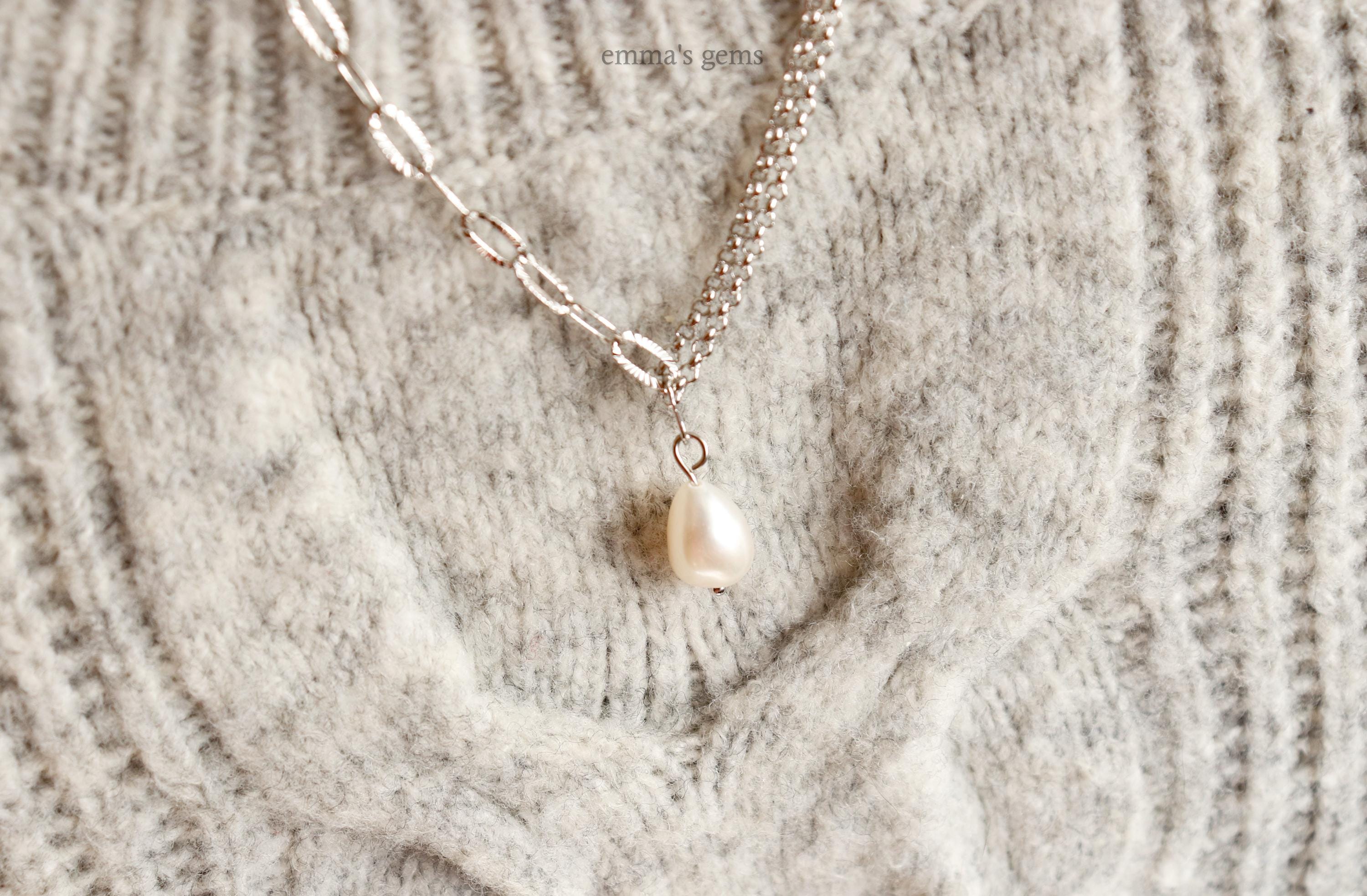 Necklace with a pearl pendant on a textured fabric background