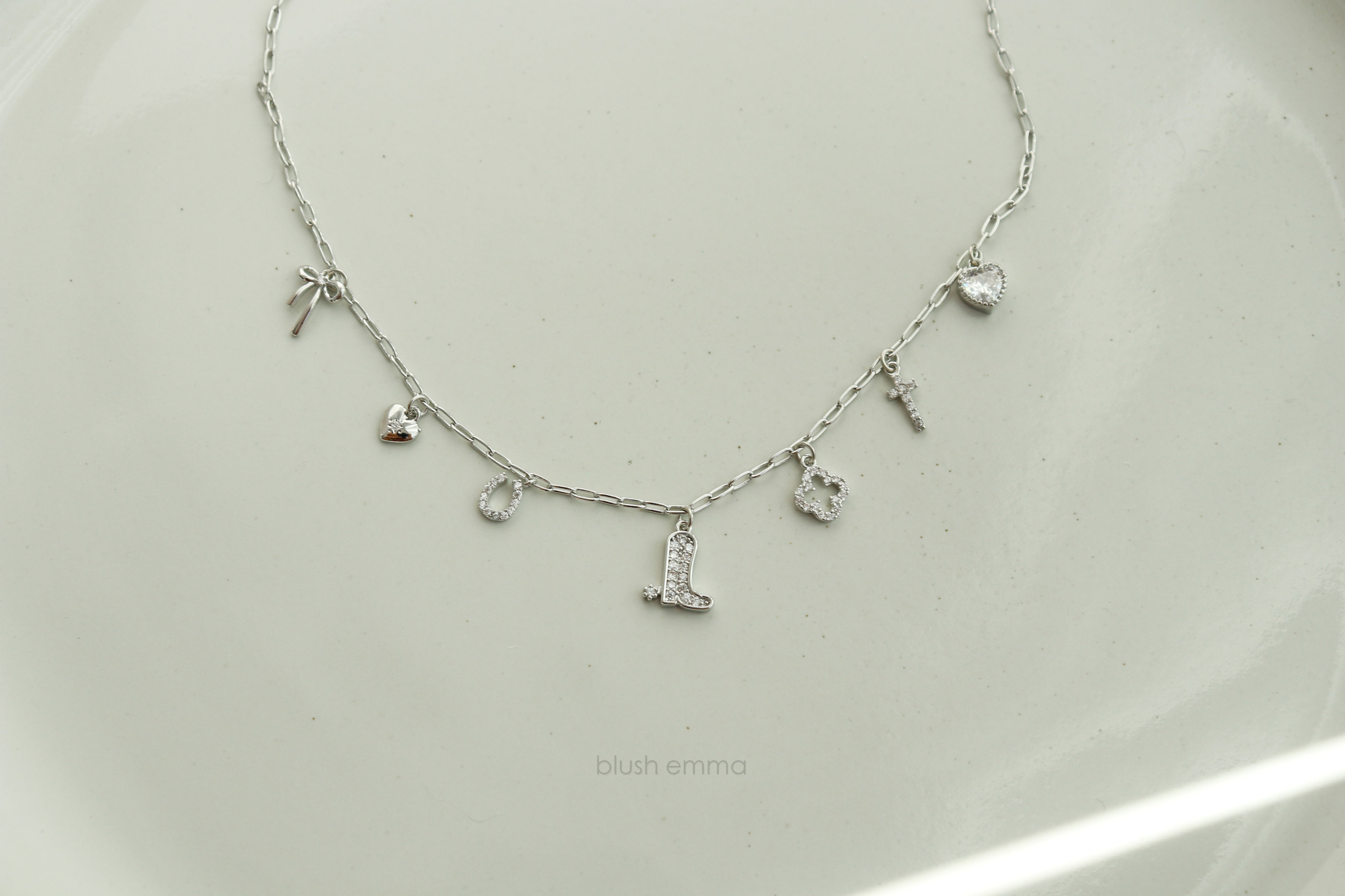 Dainty Small Sparkly Charms Station Necklace. Charms are placed on tiny paperclip chain, charms include: Ribbon, Micro Heart, Horseshoe, Boots, Clover, Cross and Crystal Heart