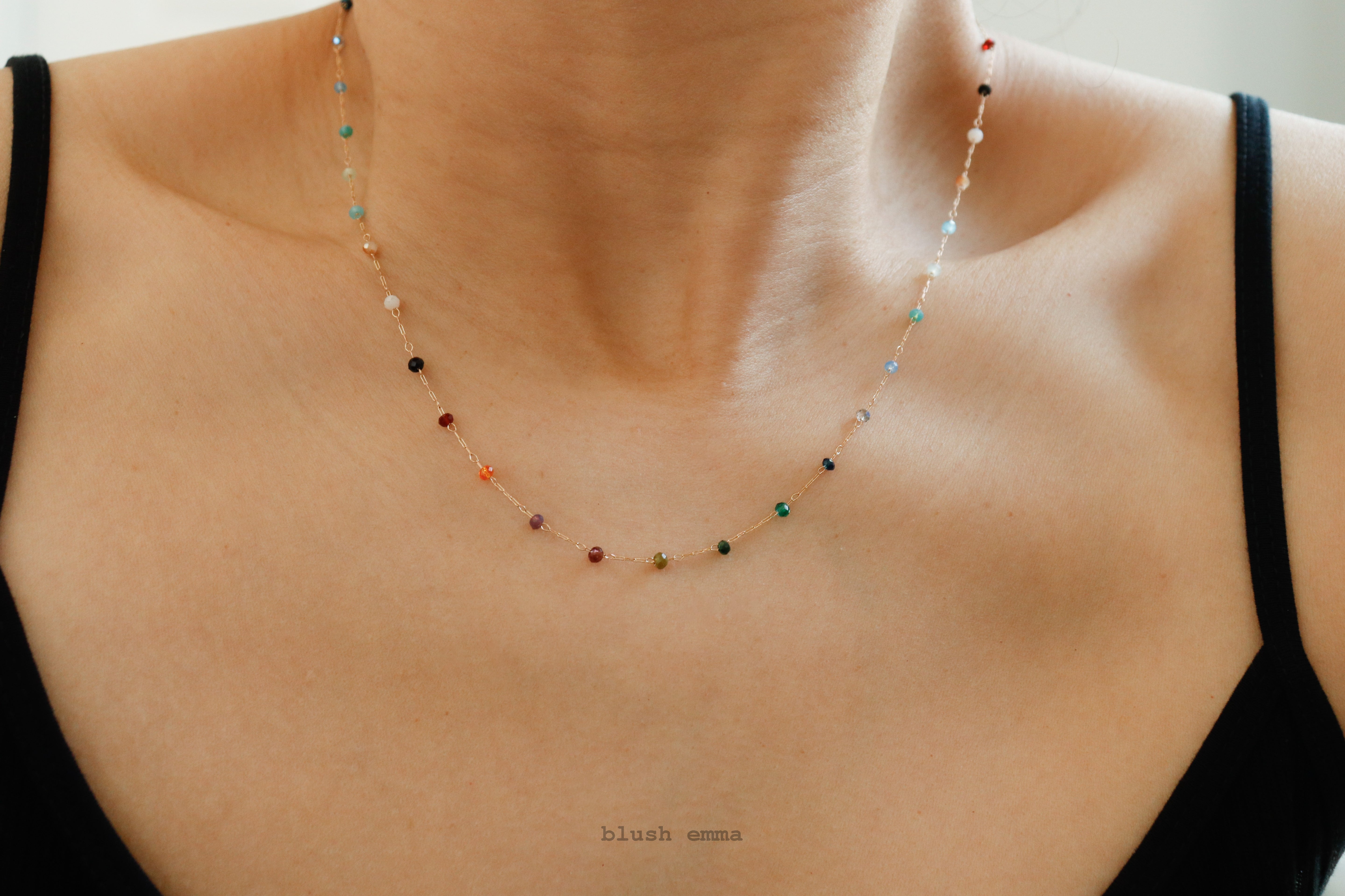 Necklace with multicolored beads on a person wearing a black top.