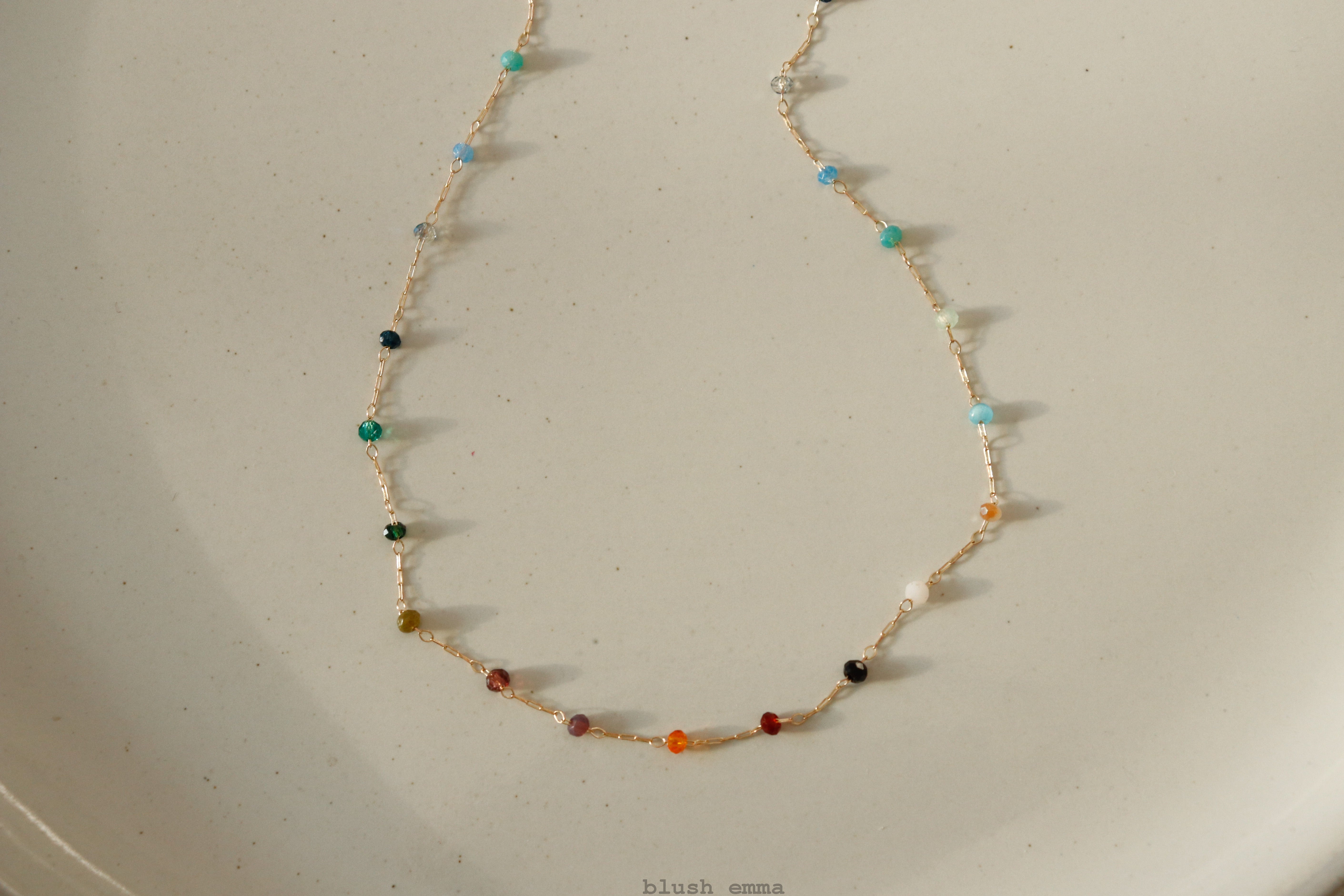blushemma Necklace with multicolored beads on a beige surface