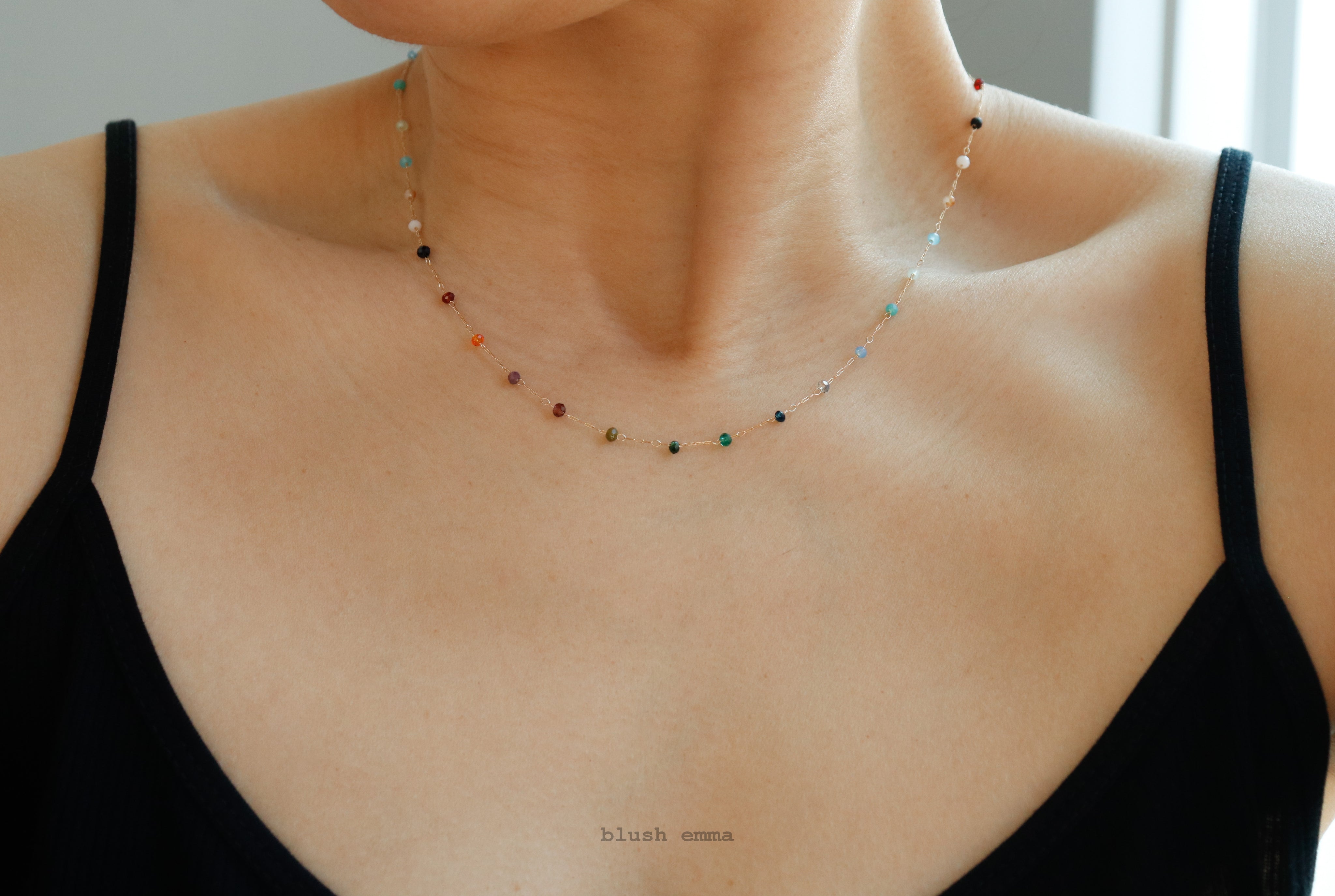 Necklace with small beads worn by a person in a black top.