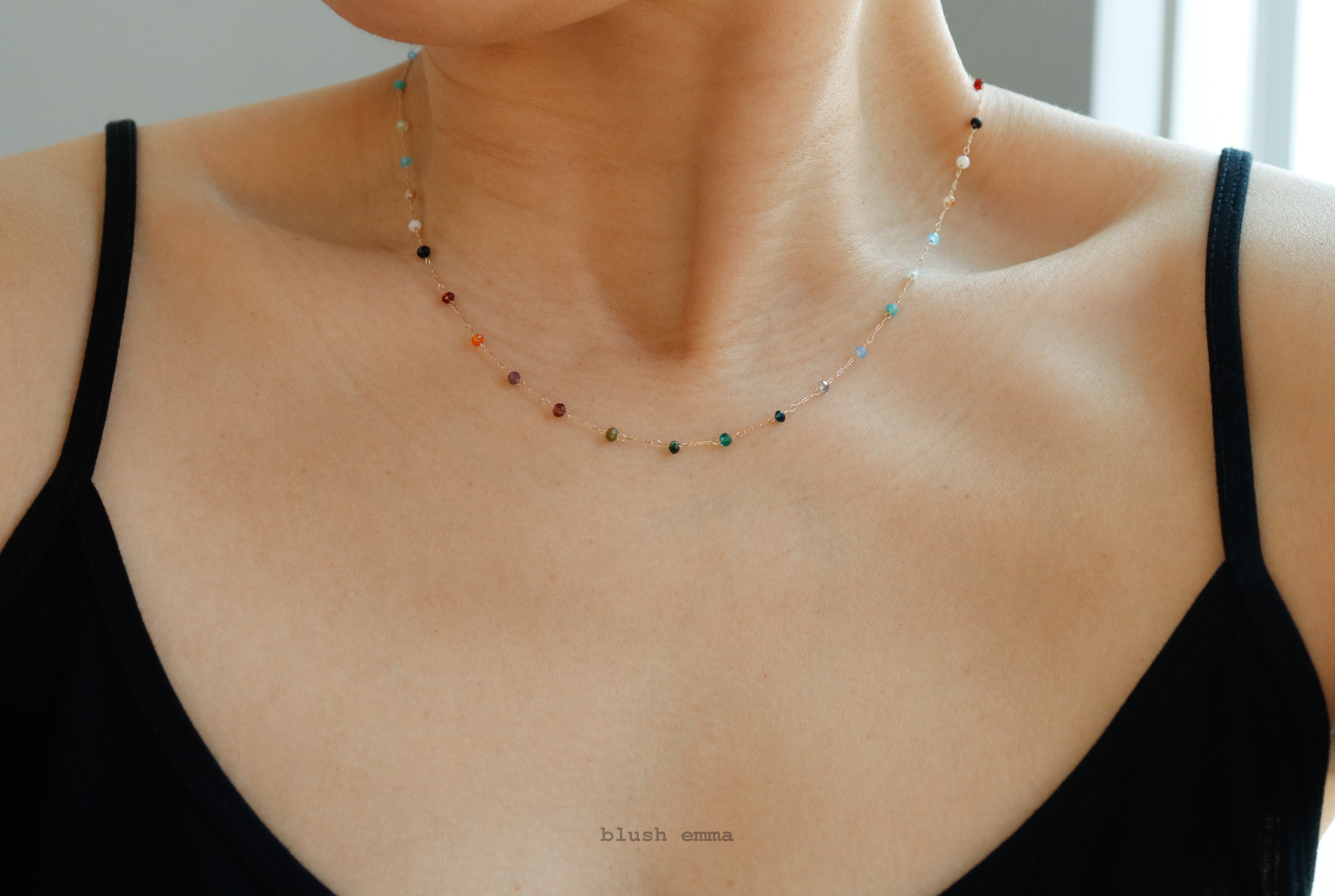 Necklace with small beads worn by a person in a black top.