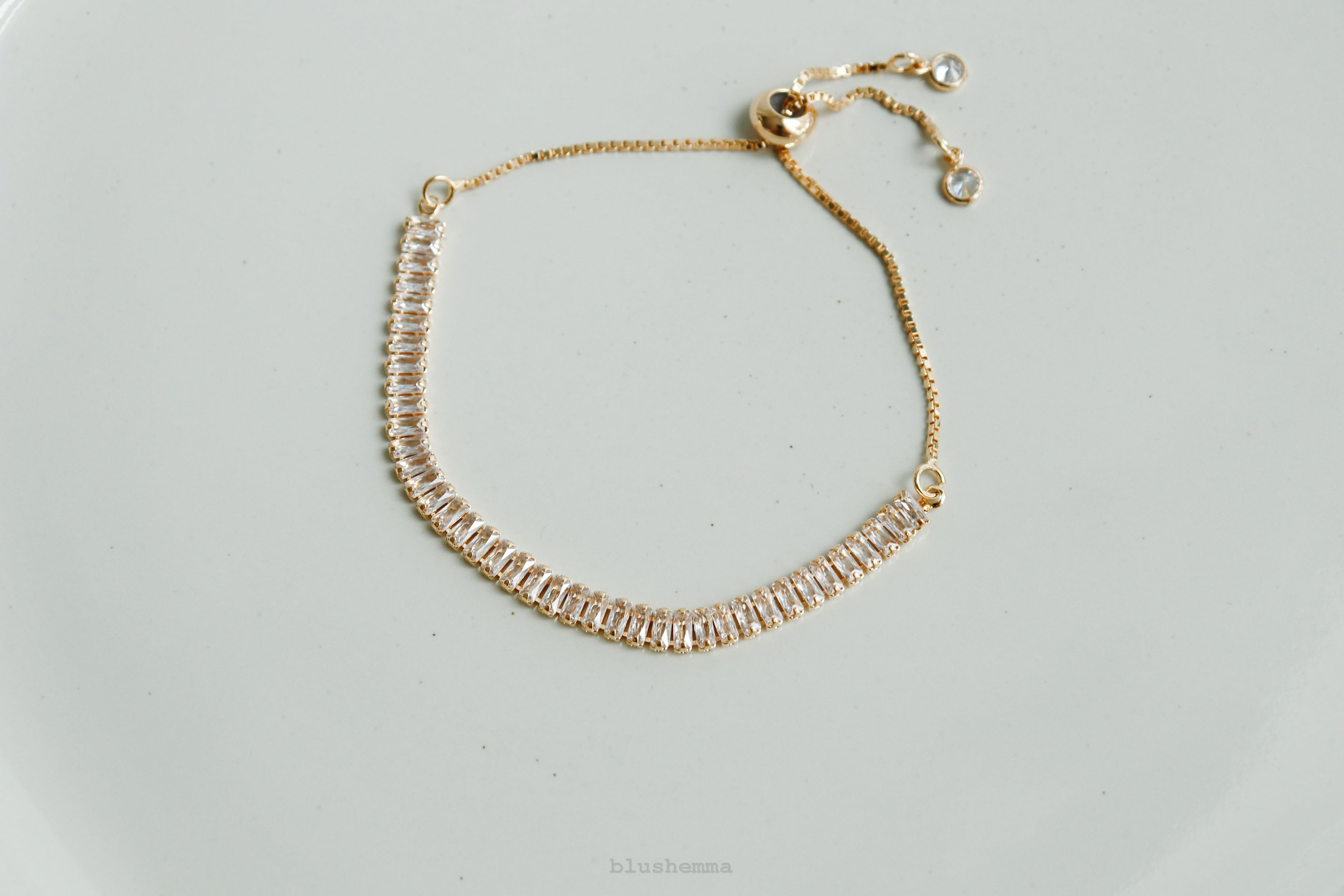 Gold bracelet with clear stones on a light gray background