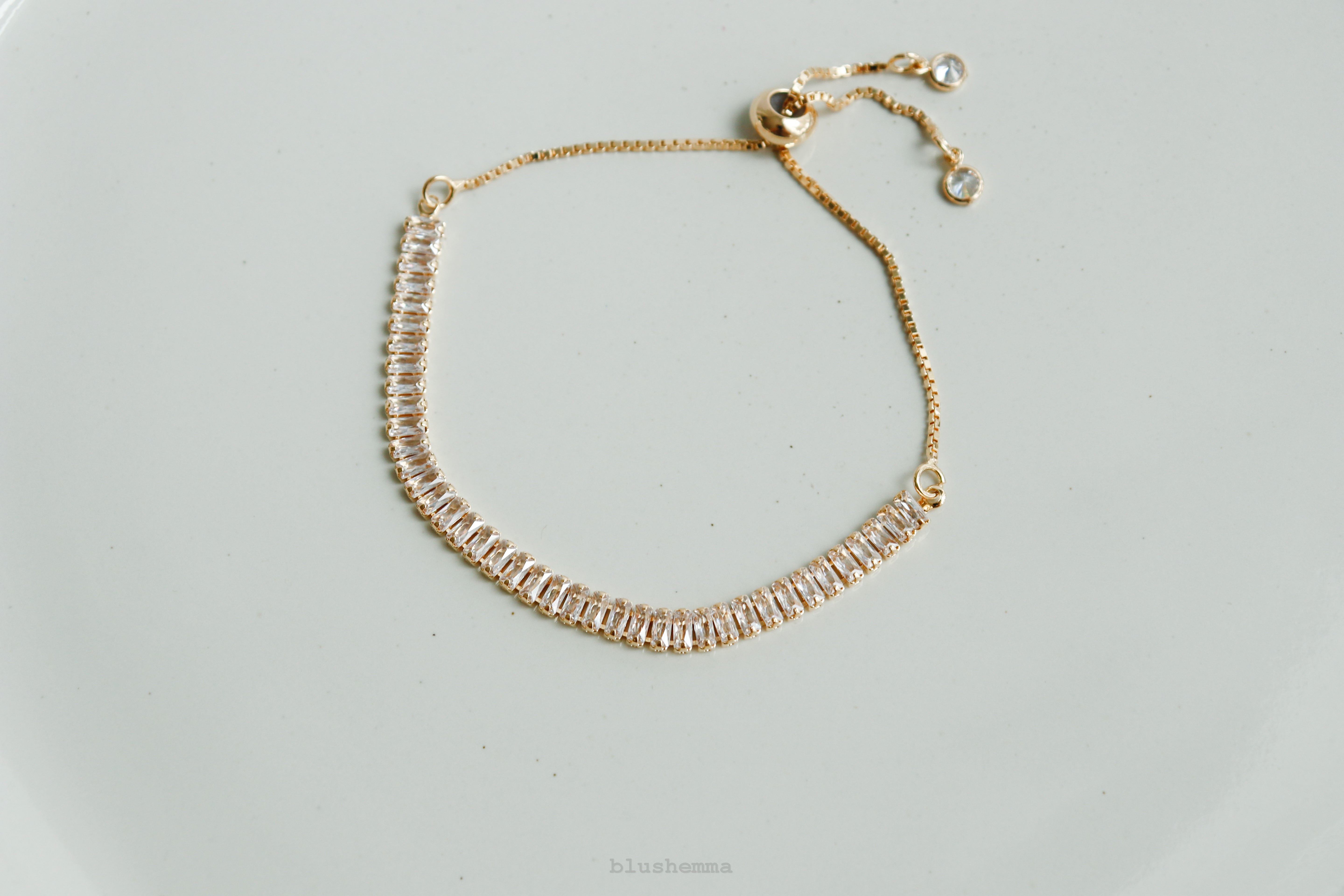 Gold bracelet with clear stones on a light gray background