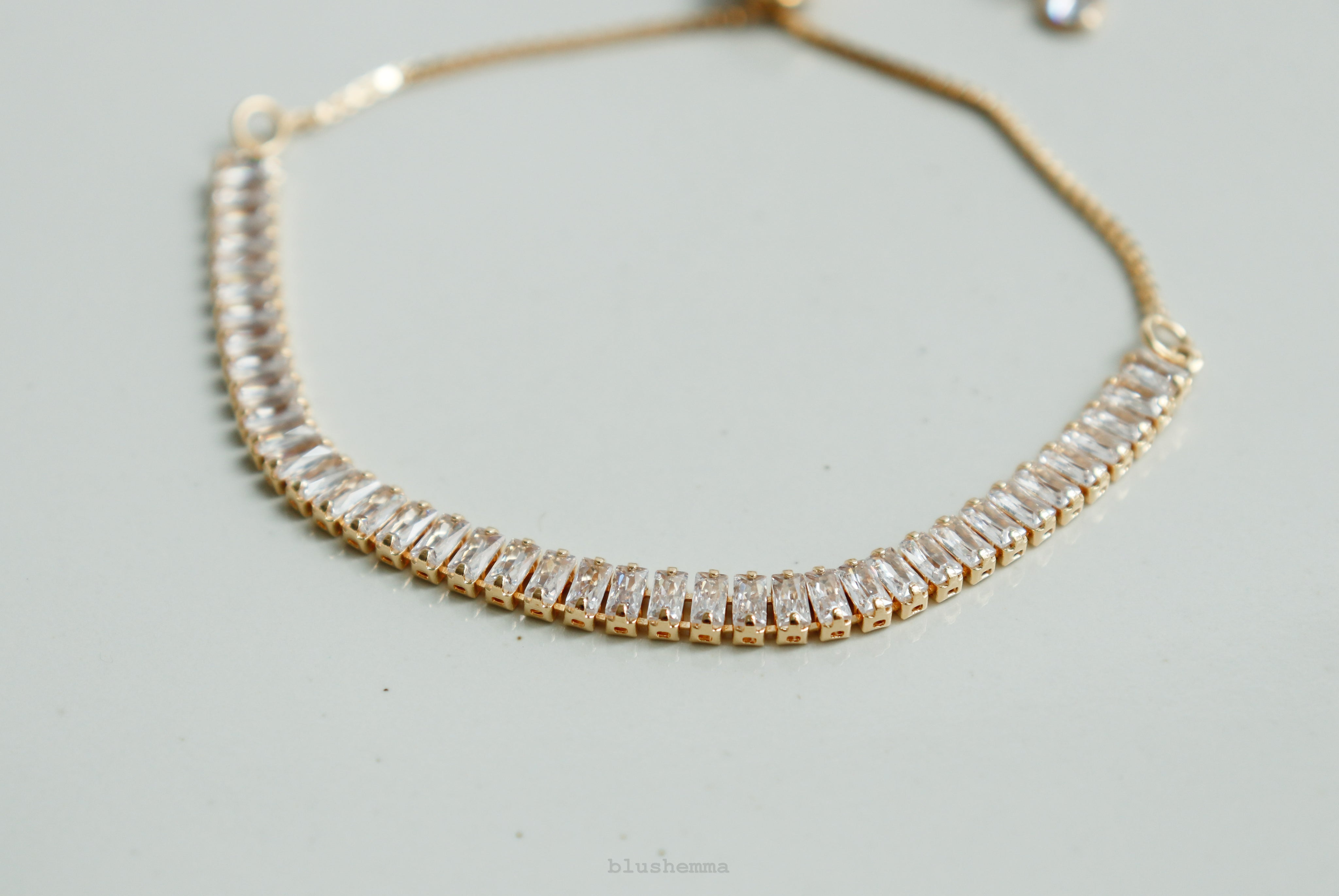 diamond baguette Gold bracelet on a wrist against a neutral background 