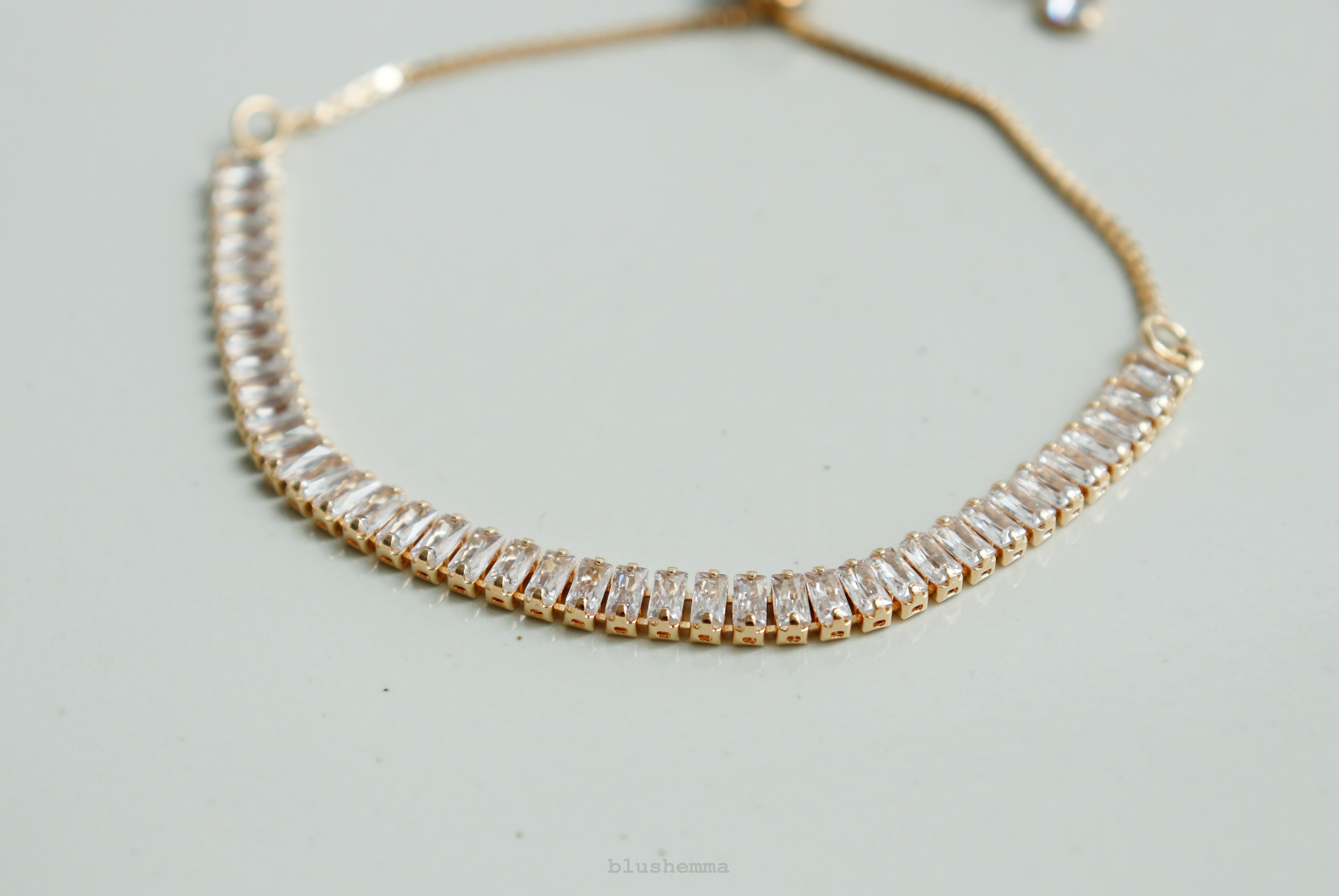 diamond baguette Gold bracelet on a wrist against a neutral background 