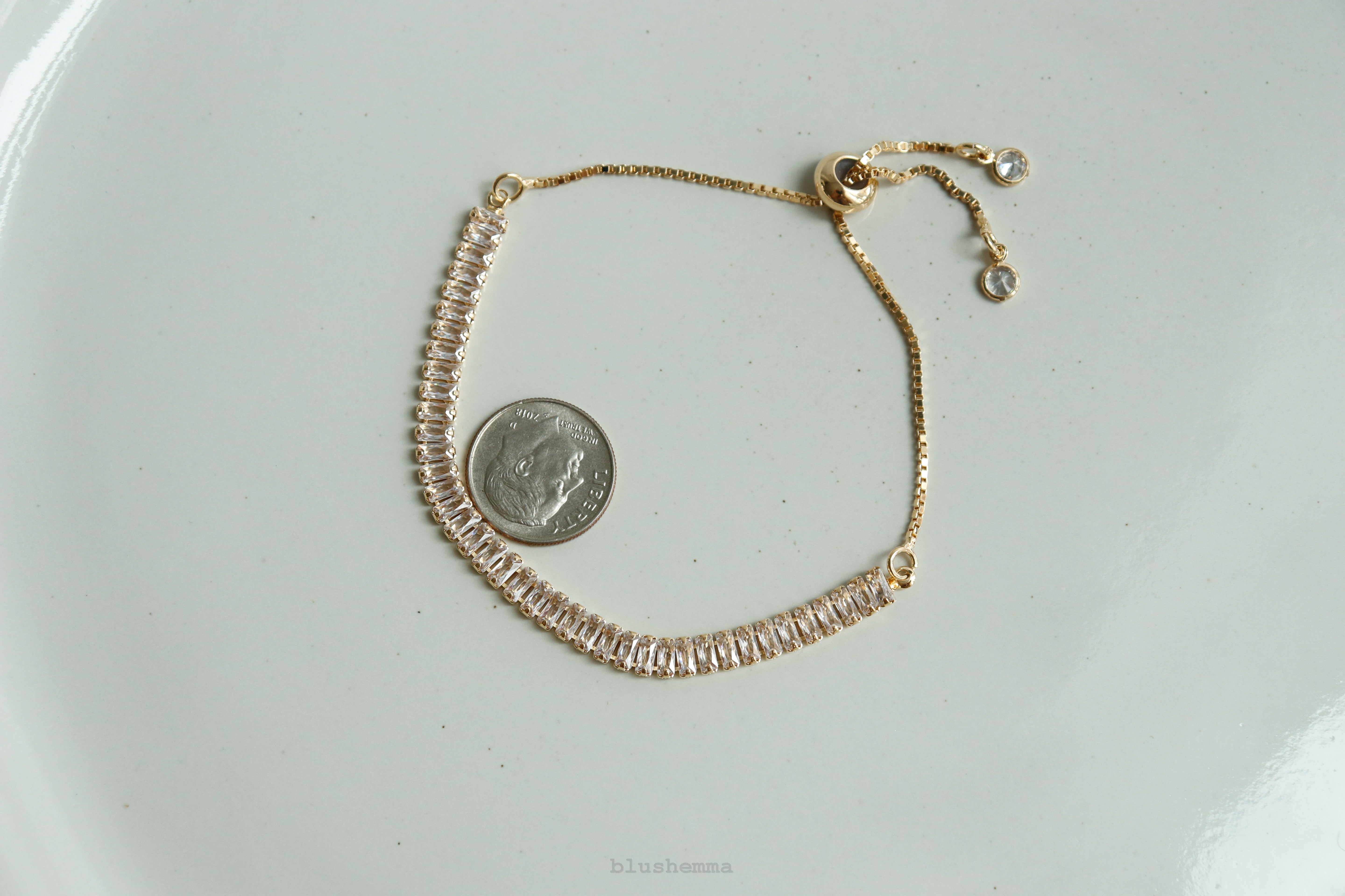 Gold bracelet with a coin for size comparison on a light gray background