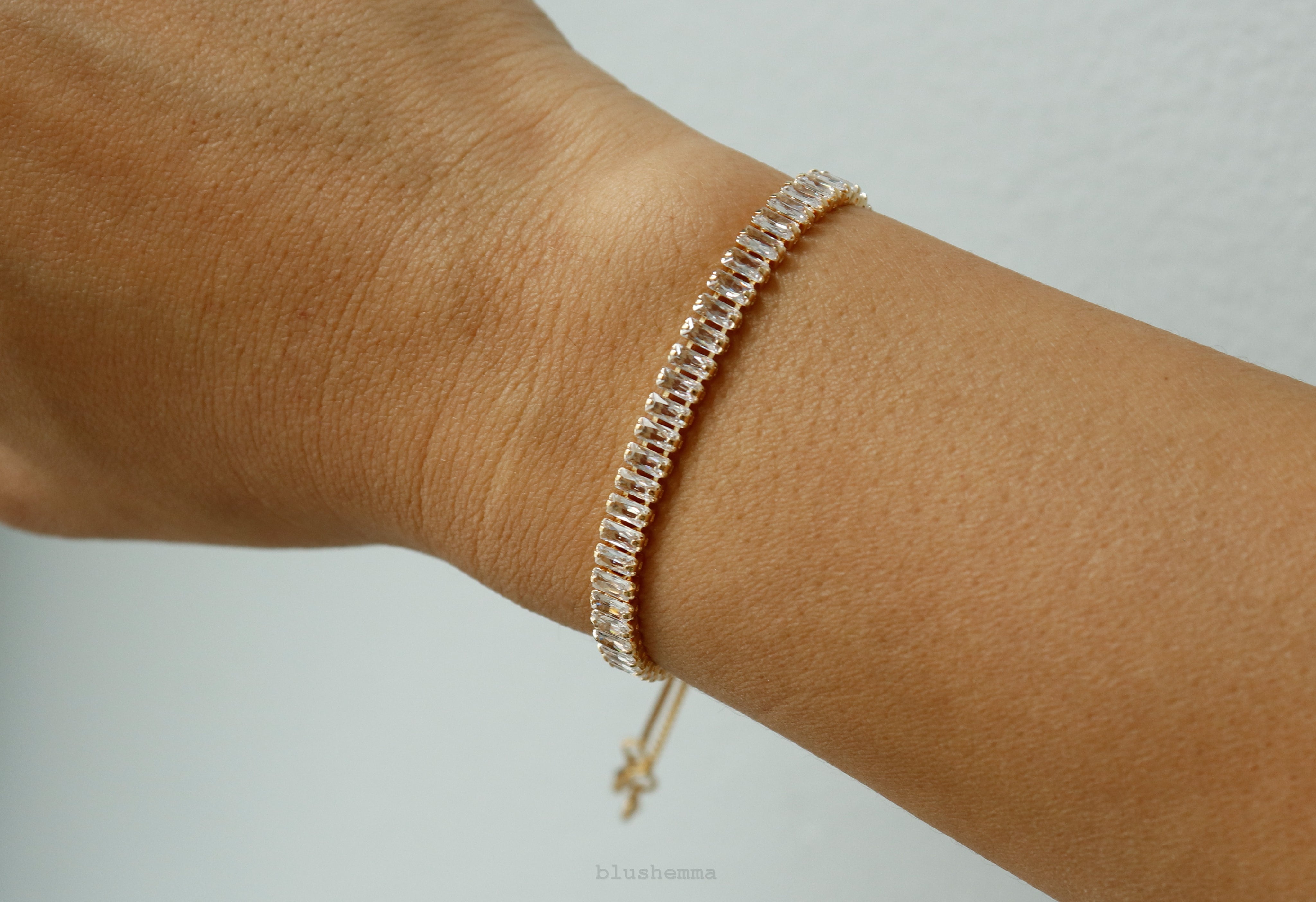 diamond baguette Gold bracelet on a wrist against a neutral background