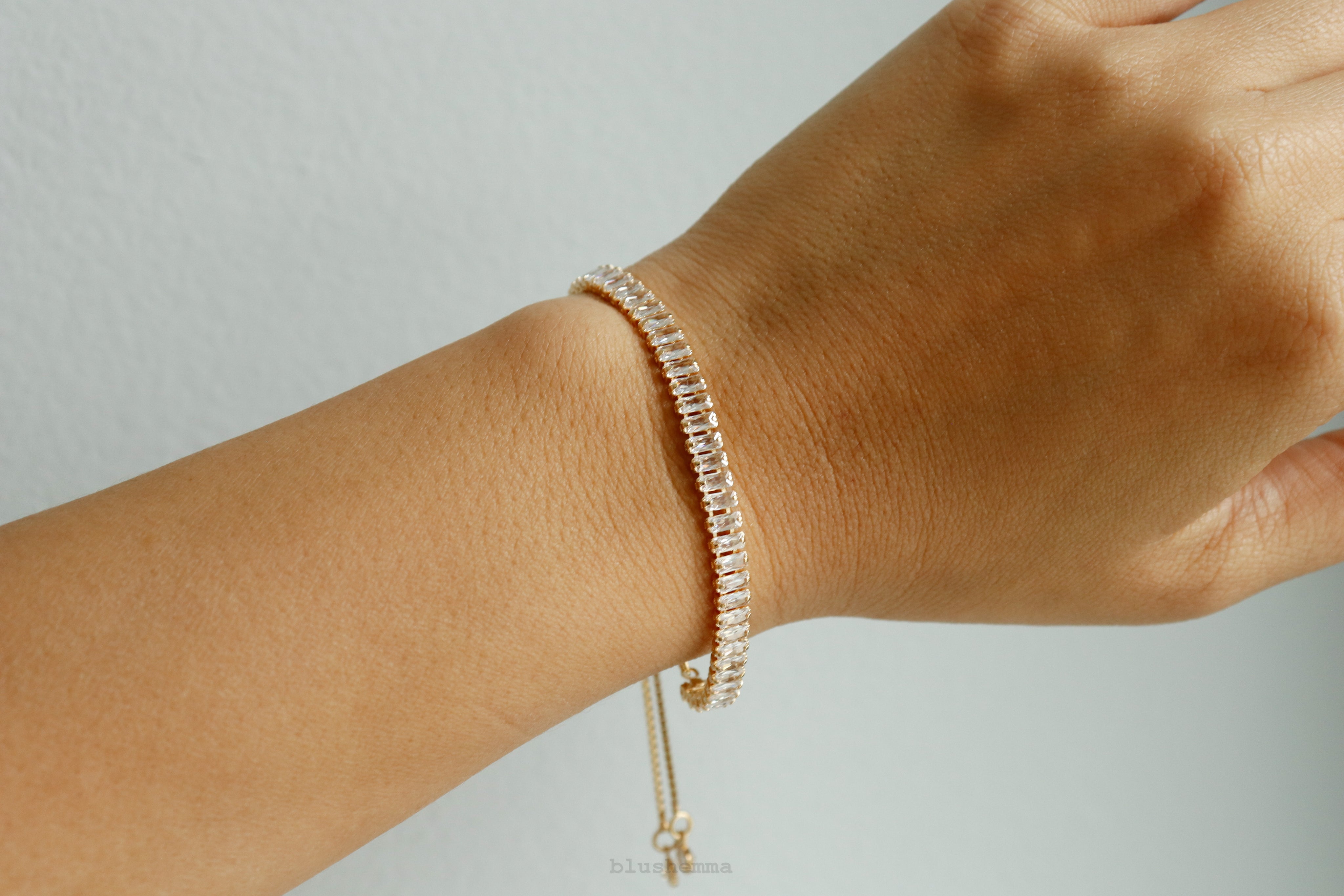 diamond baguette Gold bracelet on a wrist against a neutral background