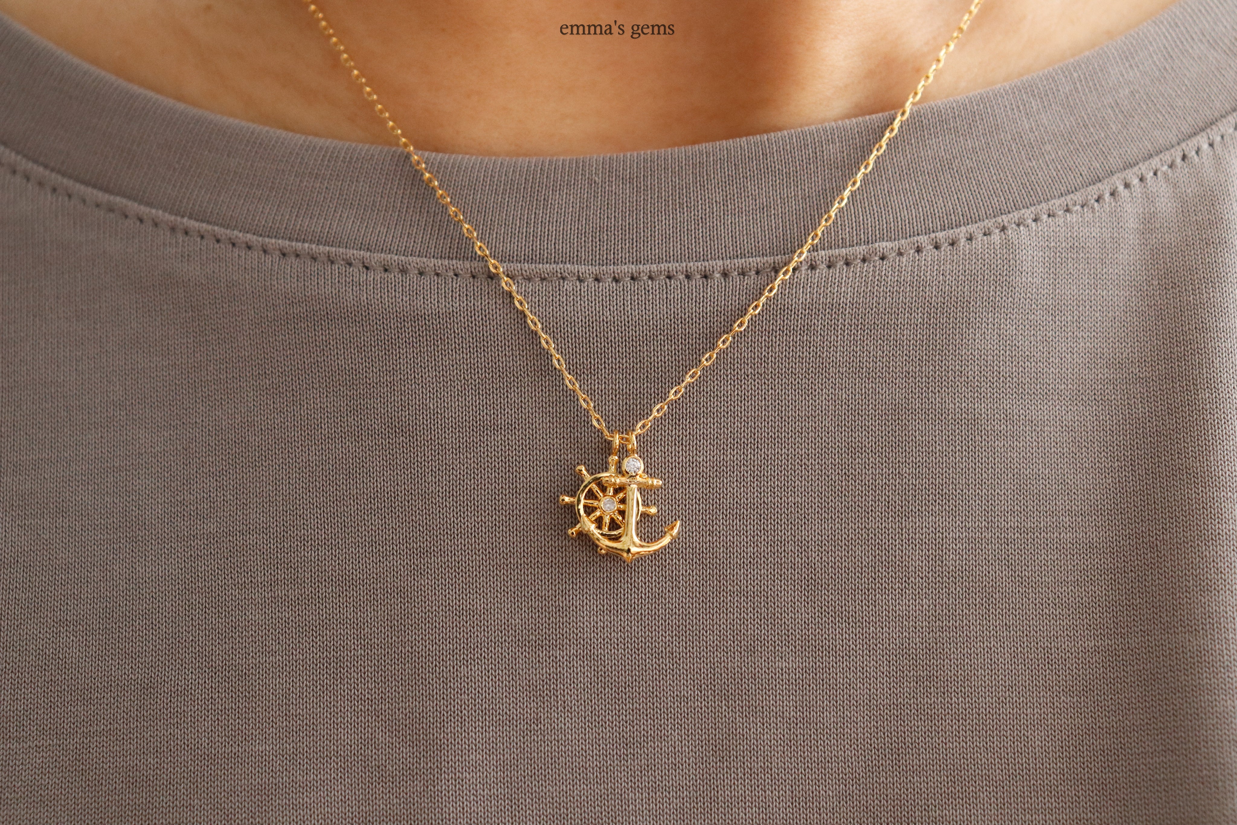 Gold Anchor and Boatwheel necklace on a gray shirt