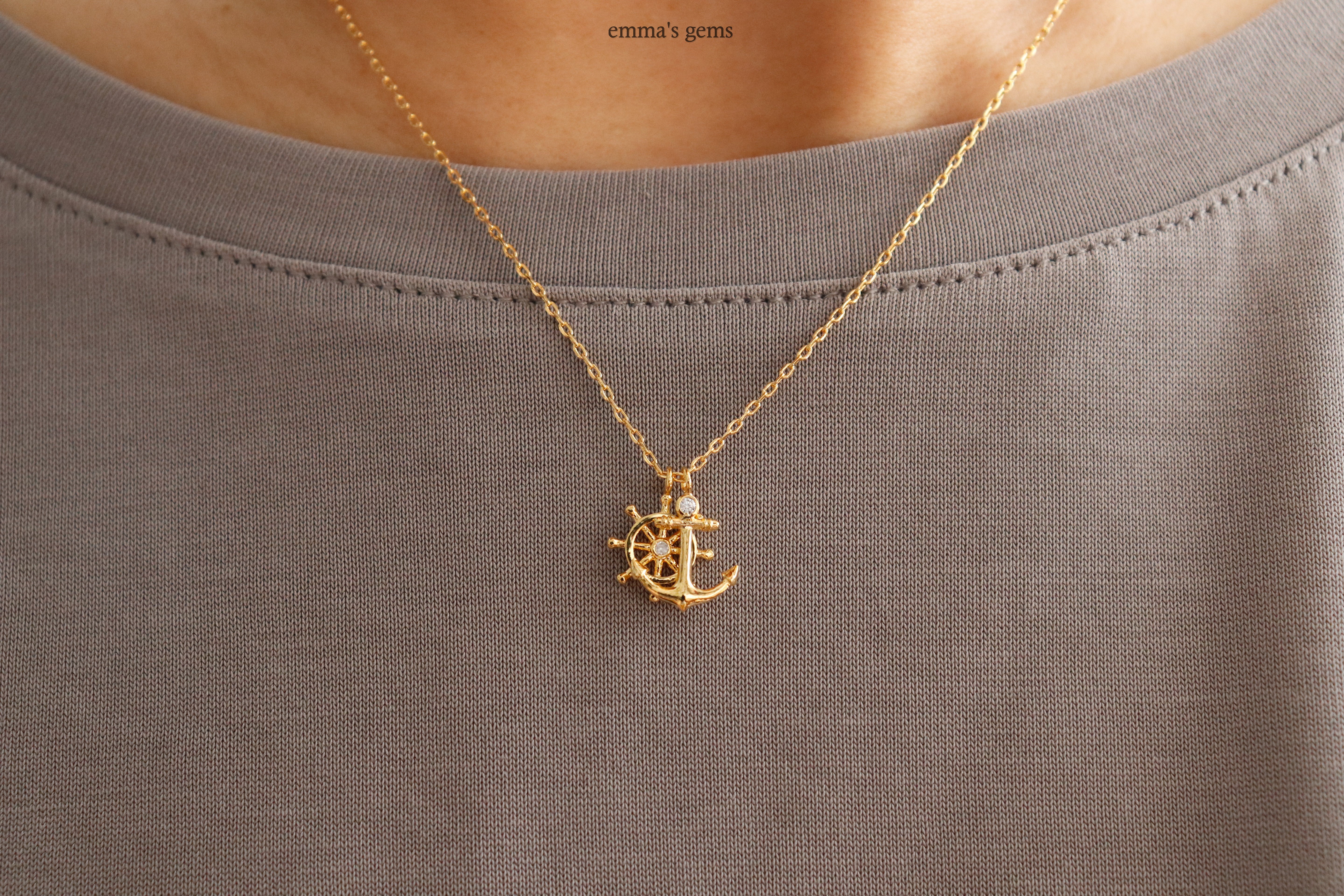 Gold Anchor and Boatwheel necklace on a gray shirt