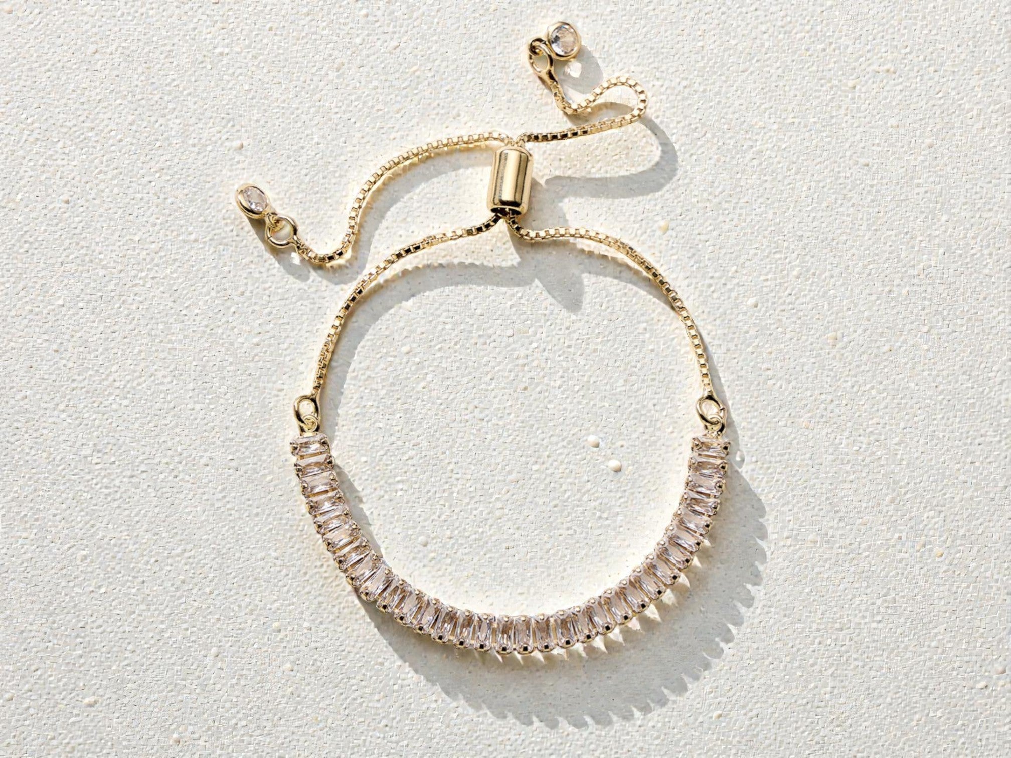 Gold bracelet with clear gemstones on a white background