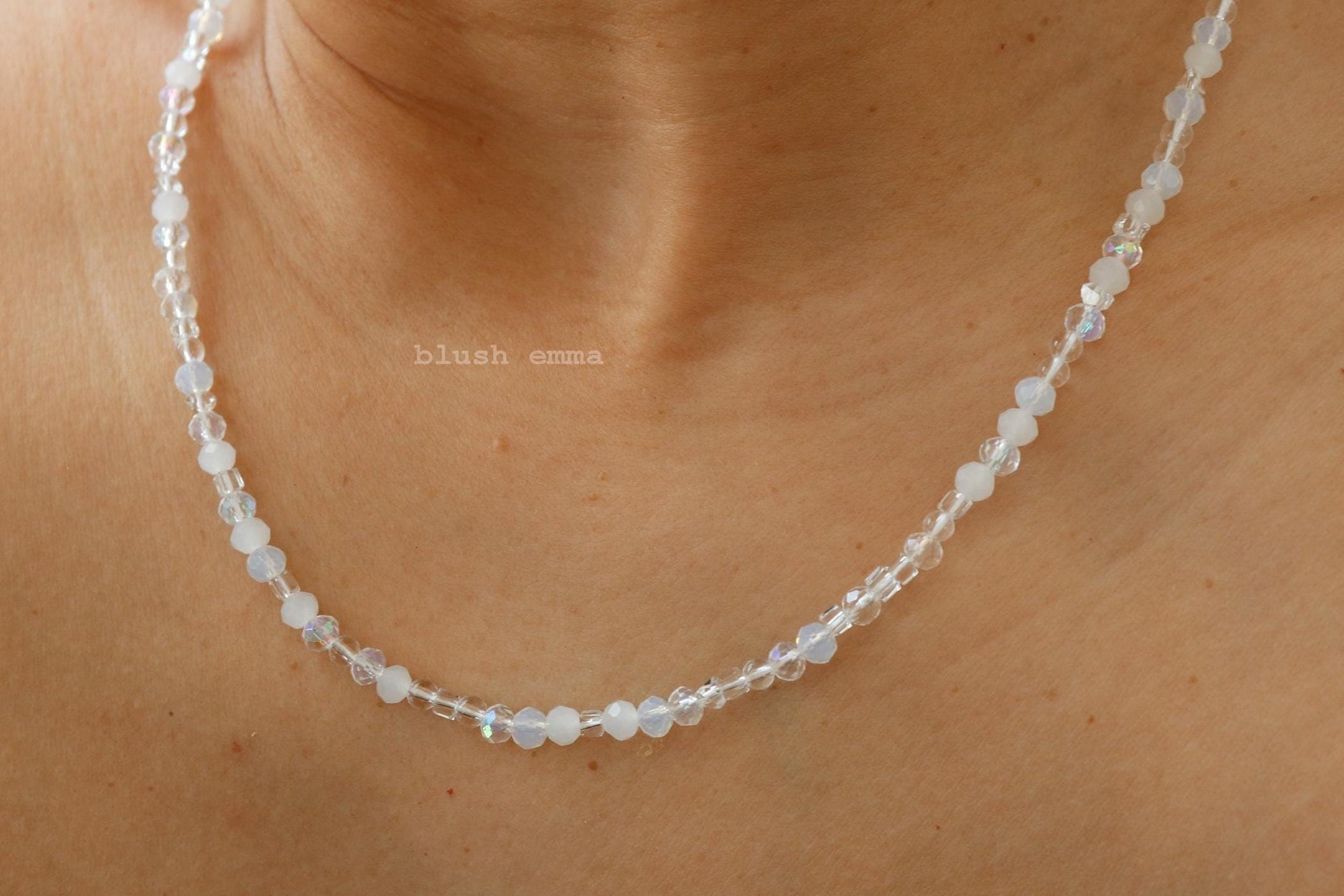 Necklace with small beads worn by a person, close-up on skin.