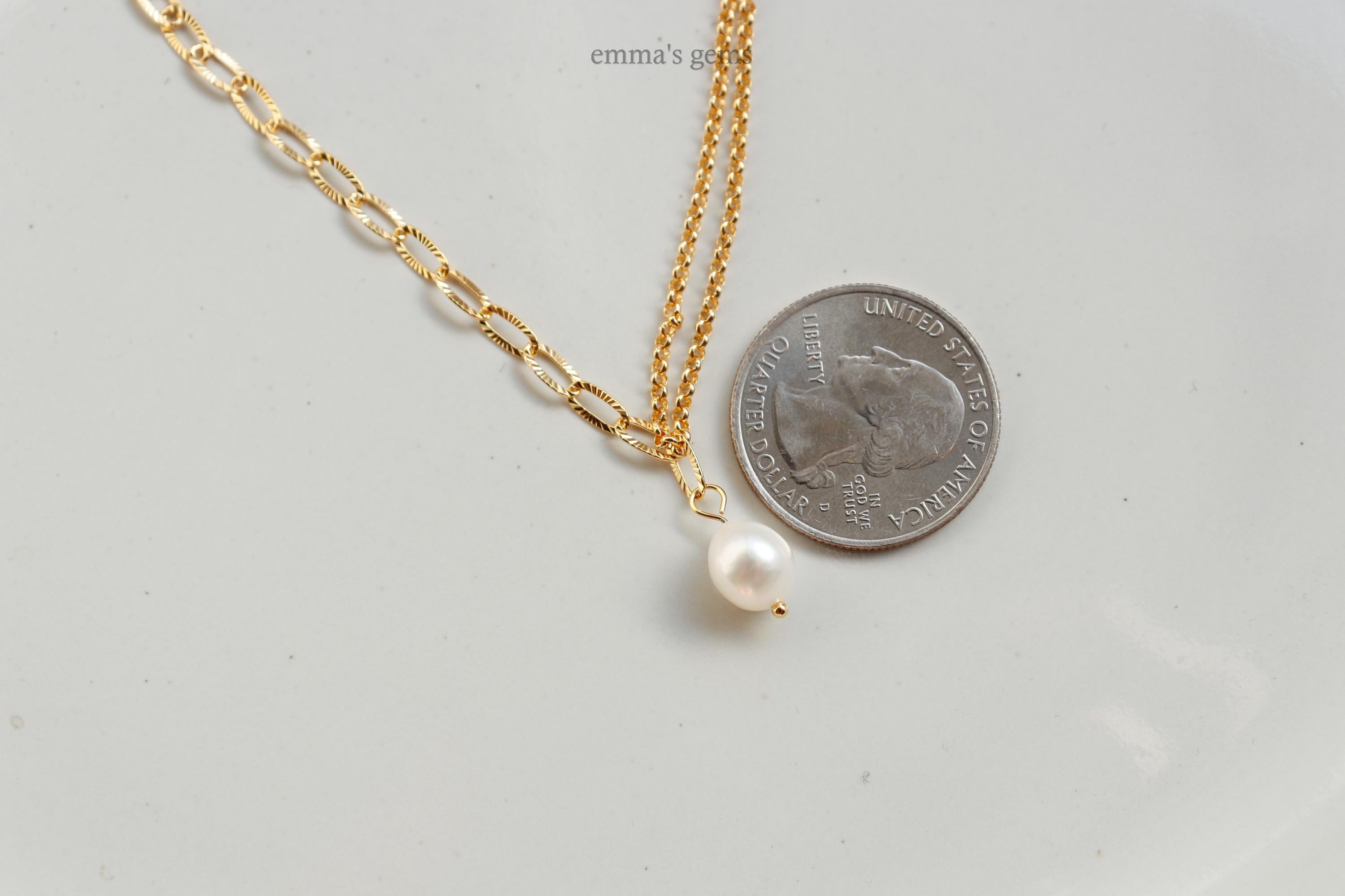 Gold necklace with a pearl pendant next to a quarter on a light gray background