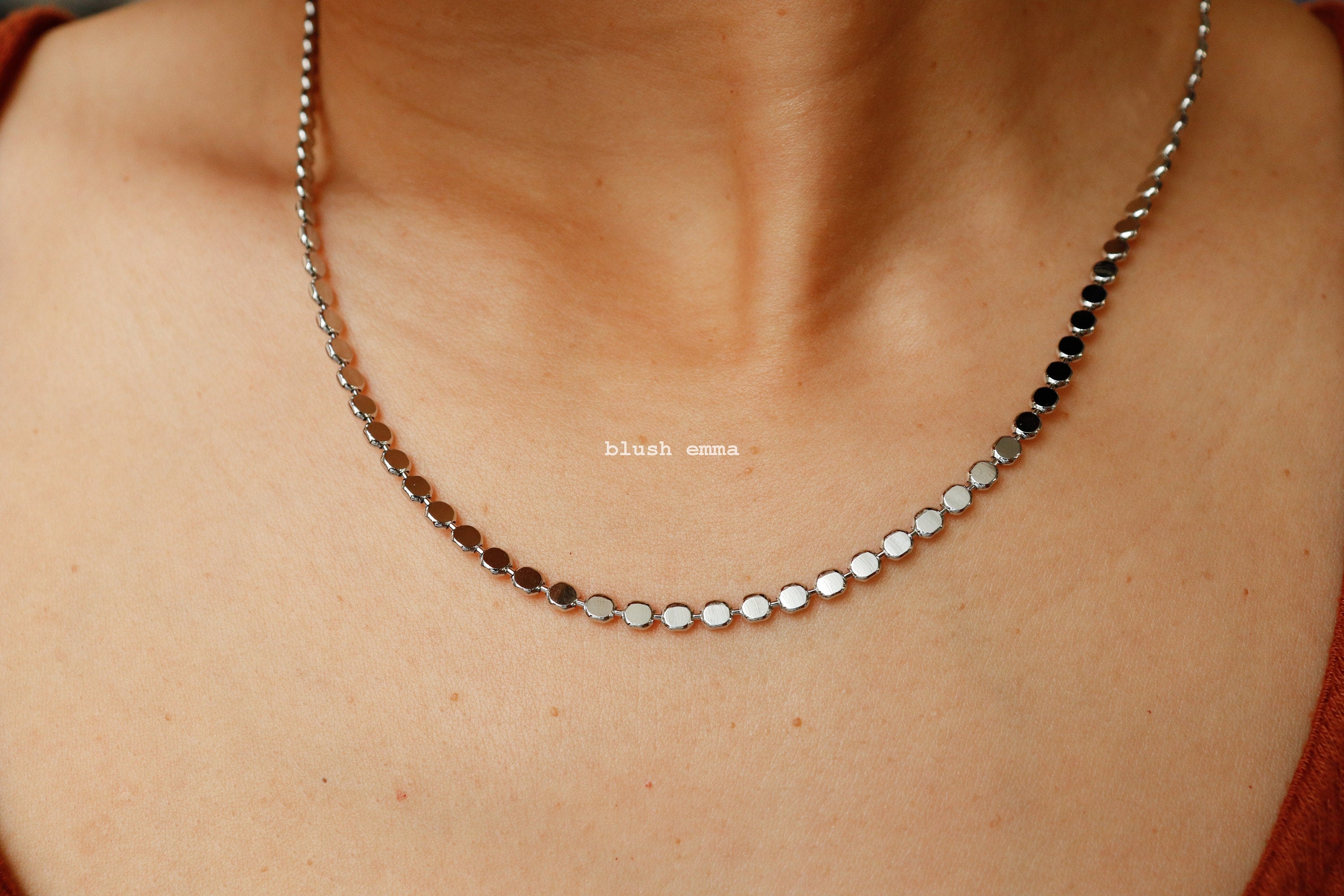 Silver necklace on a person's neck with 'blush' brand name.
