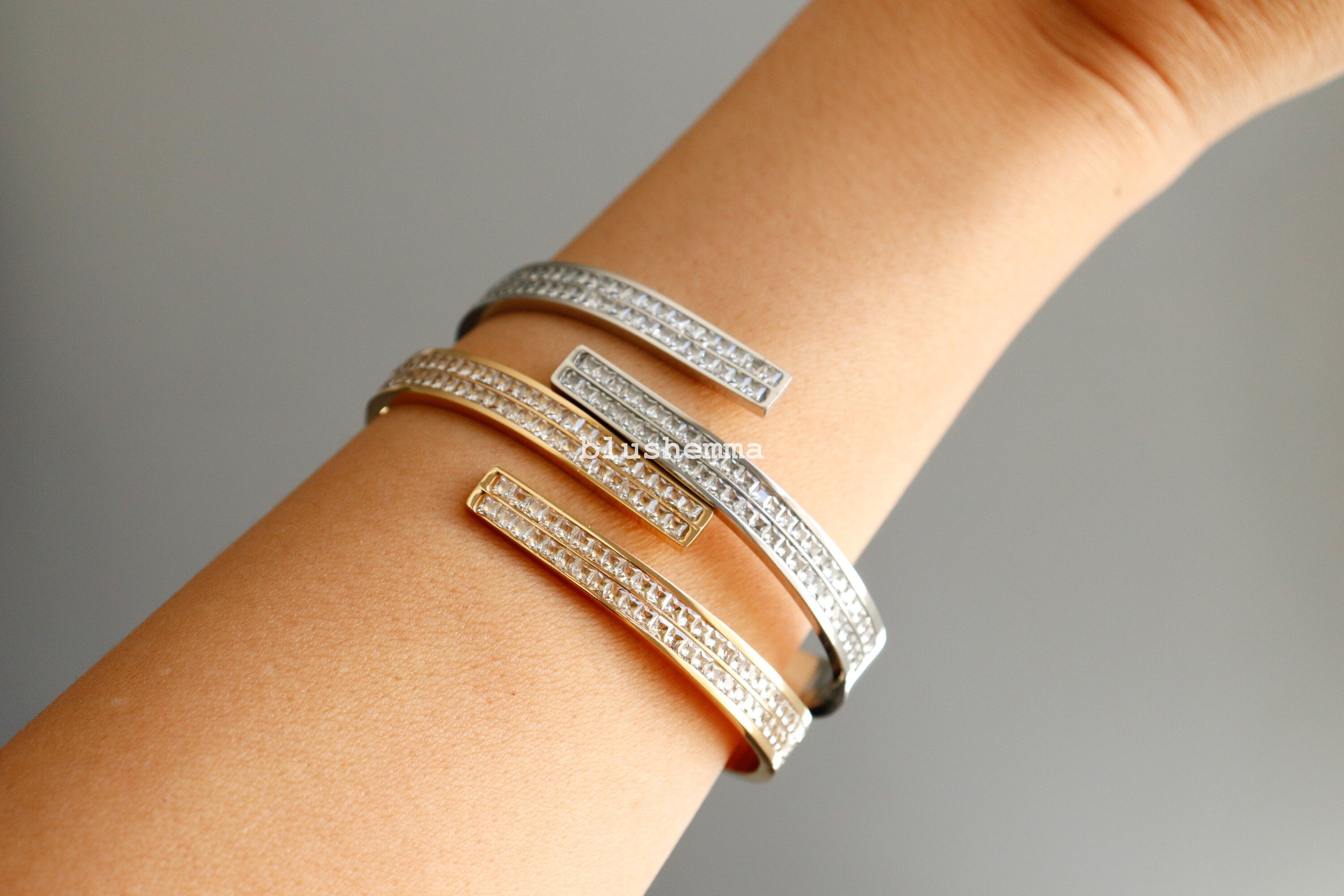 Silver bracelets on a wrist against a neutral background