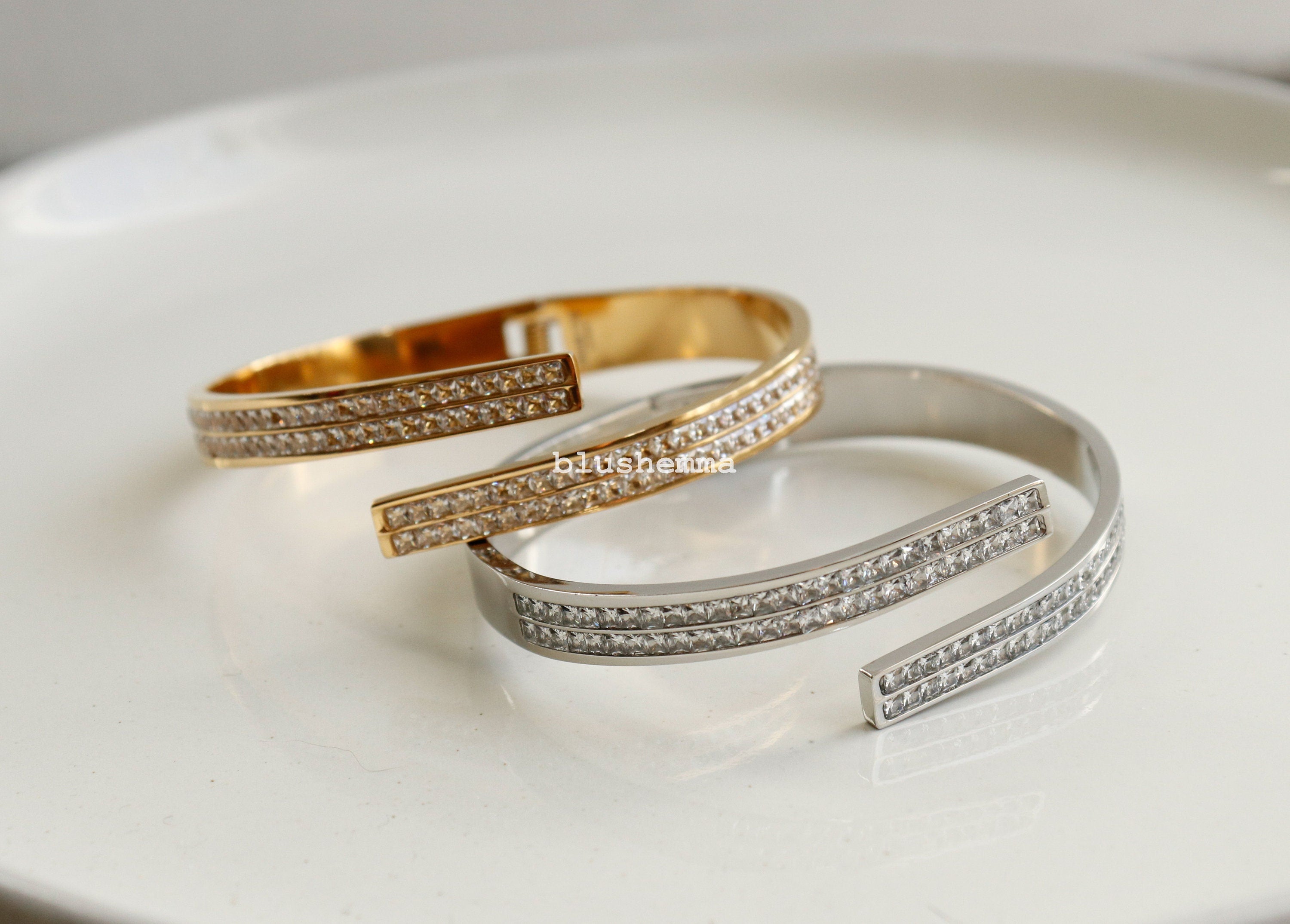 Two gold and silver bracelets with clear stones on a light background